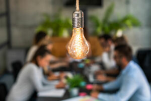 lightbult in the foreground of group of people working around a table