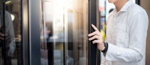 person opening glass door to enter a shop