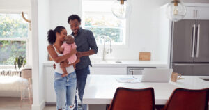 Young family in luxury kitchen setting with laptop on the counter